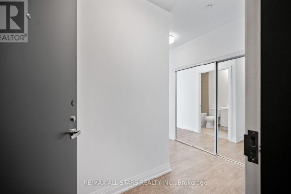 Entrance hallway with grey door, large mirrored closet, and view into a bathroom. - 315 - 286 Main Street, Toronto