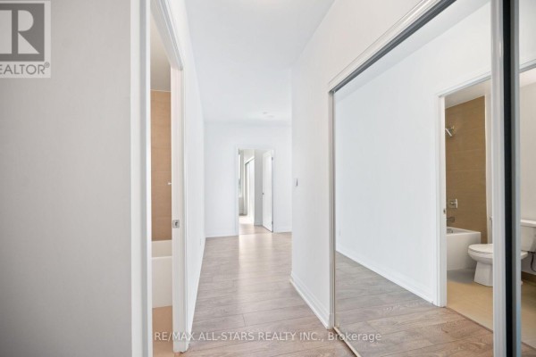 Hallway with hardwood floors, mirrored closet, and doors to rooms. - 315 - 286 Main Street, Toronto