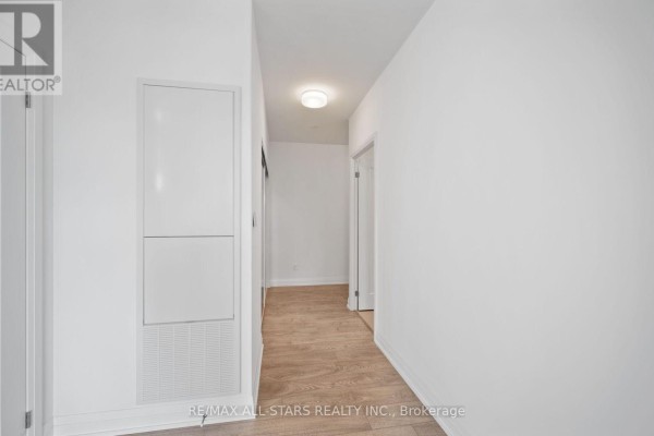 Hallway with white paneling on left wall and doors to rooms. - 315 - 286 Main Street, Toronto