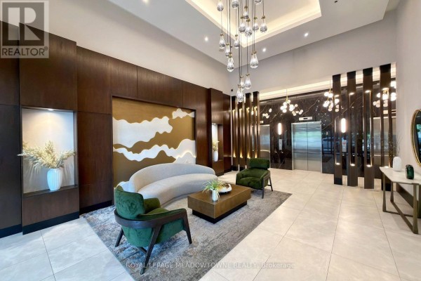 Building lobby with modern seating, decorative wall panels, and elevator doors. - 315 - 4065 Brickstone Mews, Mississauga