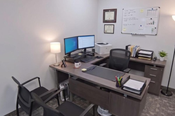 Office desk with dual monitors, computer, printer, and framed diplomas on wall. - 315 - 998 Martin Grover Road, Toronto