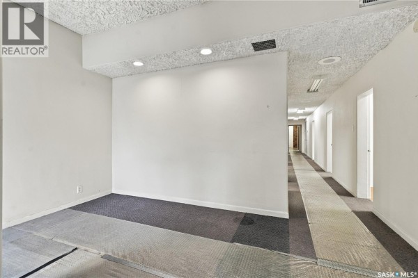 Interior view of a commercial space with white walls and a carpeted hallway. - 315 20th Street E, Saskatoon