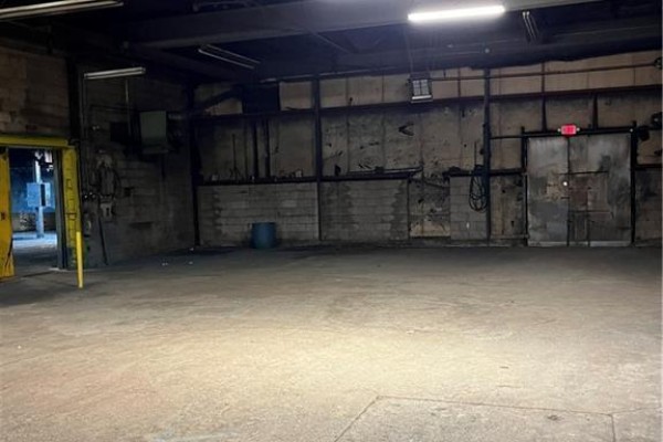 Spacious interior of a commercial unit with cinder block walls and industrial doors. - 315 Brock Road Unit# B, Dundas