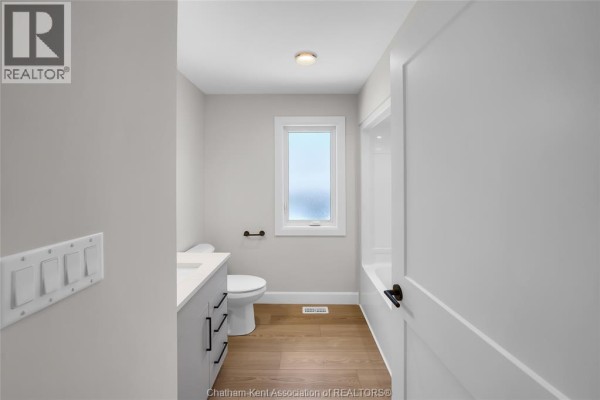 Modern bathroom with vanity, toilet, bathtub, and wood-look flooring - 315 Ironwood Trail Chatham