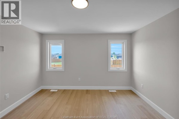 Empty room with hardwood floors and two windows - 315 Ironwood Trail Chatham