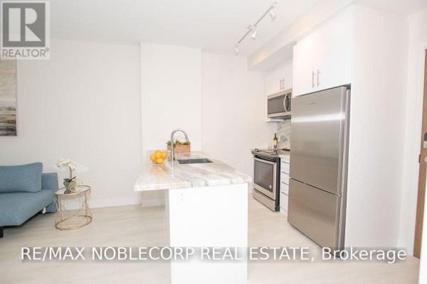 Kitchen with white cabinetry, stainless steel appliances, and a granite island. - 316 - 301 Sea Ray Avenue, Innisfil