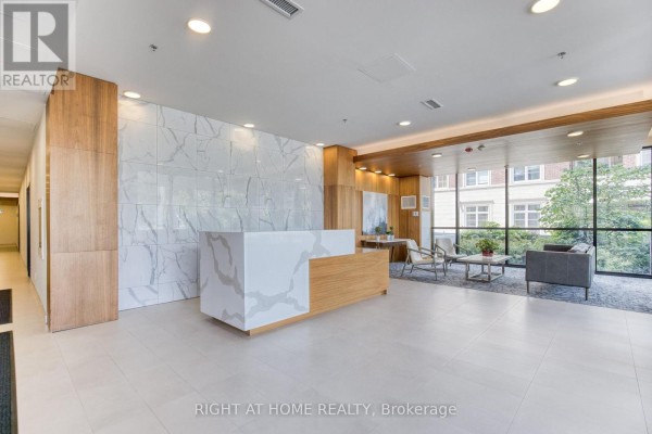 Building lobby with a white and wood reception desk, marble tile, and wood paneling. - 316 - 50 Ann Street, Caledon