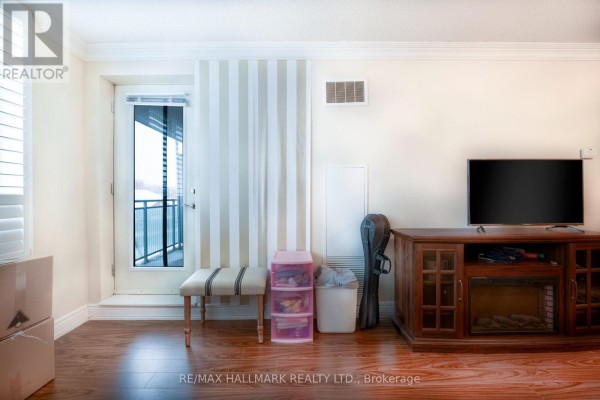Living room area featuring a television, fireplace, and a door to the balcony. - 316 - 62 Suncrest Boulevard, Markham