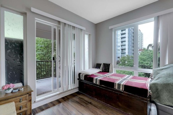 Apartment room with large windows, balcony door, and view of buildings. - 316 13339 102a Avenue, Surrey