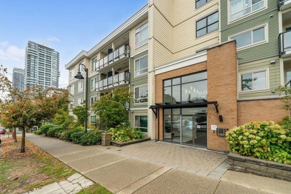 Apartment building exterior with manicured landscaping and paved walkway leading to entrance. - 316 13789 107a Avenue, Surrey