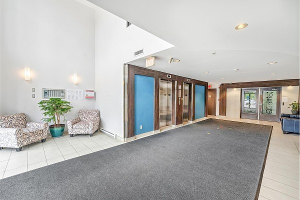 Building lobby with elevator doors, seating area, and tile flooring. - 316 13789 107a Avenue, Surrey