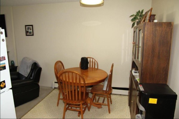 Dining area with round wooden table and four chairs, adjacent to a china cabinet. - 316 45749 Spadina Street, Chilliwack Downtown, Chilliwack