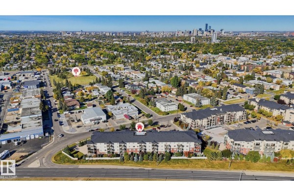Aerial view of apartment buildings in a suburban neighborhood with a distant city skyline. - #316 7711 71 St Nw, Edmonton