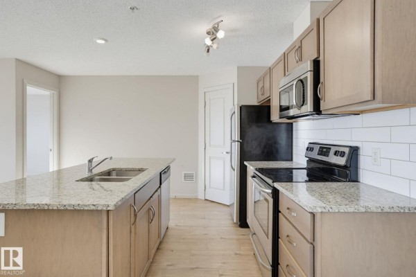 Kitchen with light wood cabinets, stainless steel appliances, granite countertops, and white subway tile backsplash. - #316 7711 71 St Nw, Edmonton