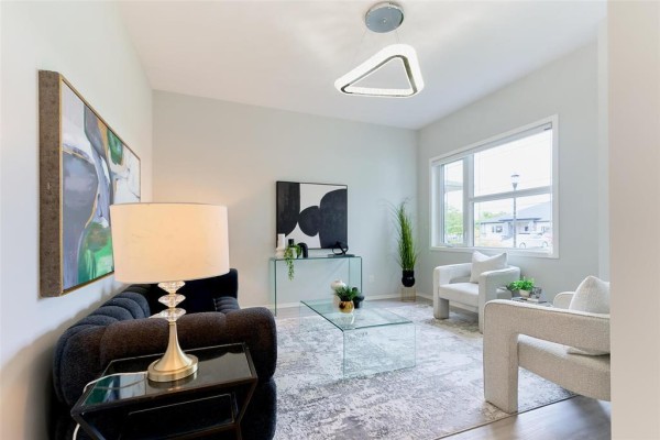 Interior view of a living room with light grey walls, a grey rug, and glass furniture. - 316 Creekside Road, Winnipeg