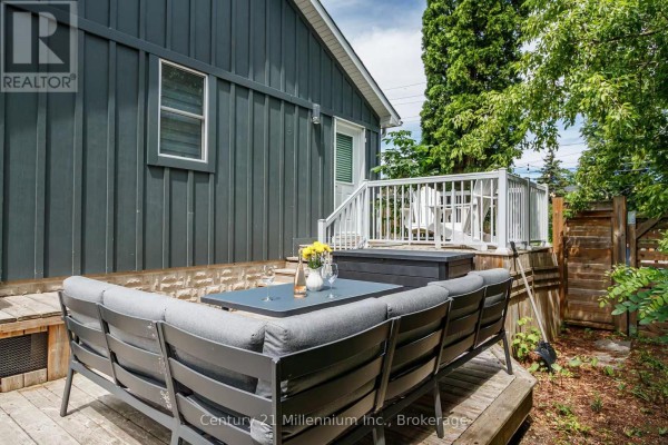 Wooden deck with grey outdoor sofa, table, and storage box surrounded by trees. - 316 Hume Street, Collingwood