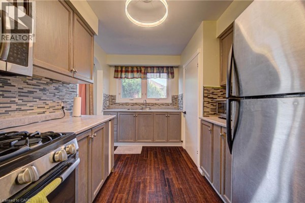 Kitchen with light grey wood cabinets, stainless steel appliances, grey quartz countertops, and a mosaic tile backsplash. - 3160 Binbrook Road, Binbrook