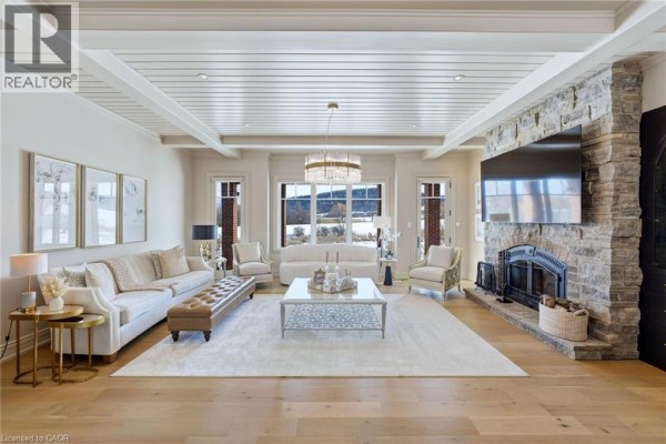 Bright living room with coffered ceiling, chandelier, and stone fireplace - 3160 Britannia Road, Burlington