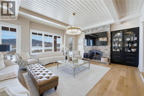 Living room featuring large windows, stone fireplace, and modern furniture arrangement - 3160 Britannia Road, Burlington