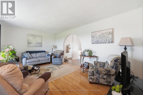 Living room with fireplace, archway to hallway, and hardwood floors. - 3160 Dunning Road, Ottawa
