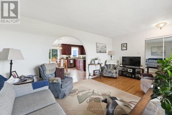 Living room with arched doorway to kitchen, featuring seating, TV, and wood floors - 3160 Dunning Road Ottawa