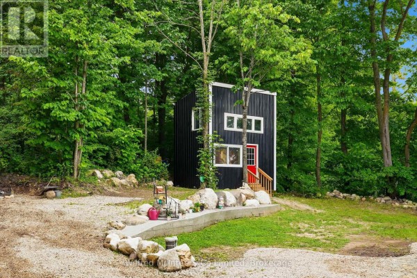 Modern black tiny home with red door, trees, and landscaping - 316040 6 Highway Chatsworth