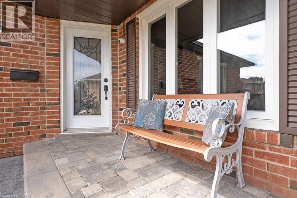 Close-up of a front door with a decorative glass insert and a wooden bench outside. - 3163 Barwell Road, Mississauga