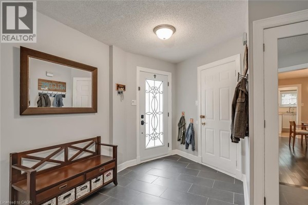 Interior entryway with gray walls, dark gray tile floor, and a wooden bench. - 3163 Barwell Road, Mississauga