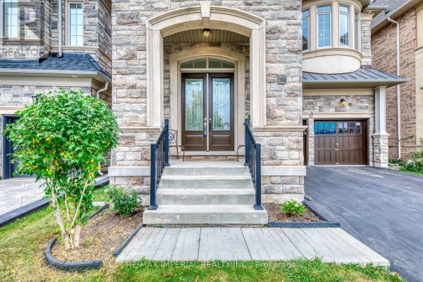 Close-up of the stone-clad front entrance with double glass doors and black railings. - 3164 Post Road, Oakville