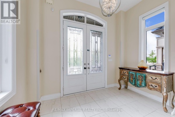 Interior view of the foyer with double white doors, tiled floor, and console table. - 3164 Post Road, Oakville