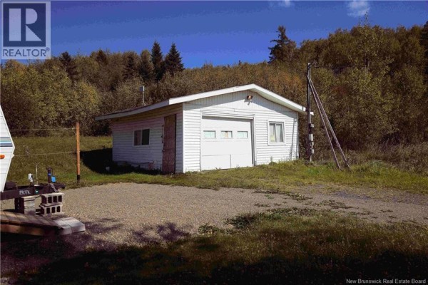 White detached garage with a white overhead door and two windows, surrounded by grass. - 3164 Route 108, New Denmark