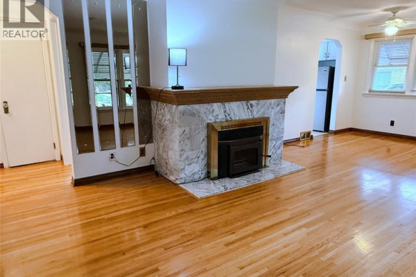 Living room with a marble fireplace, wood floors, and mirrored partition. - 3168 Church, Windsor
