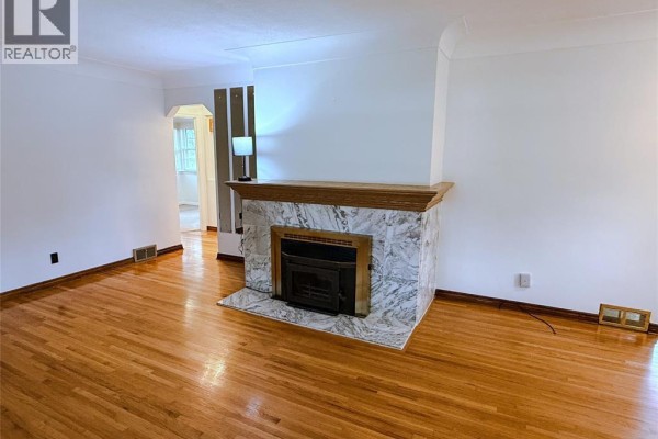 Living room with a fireplace, wood floors, and large windows overlooking the yard. - 3168 Church, Windsor