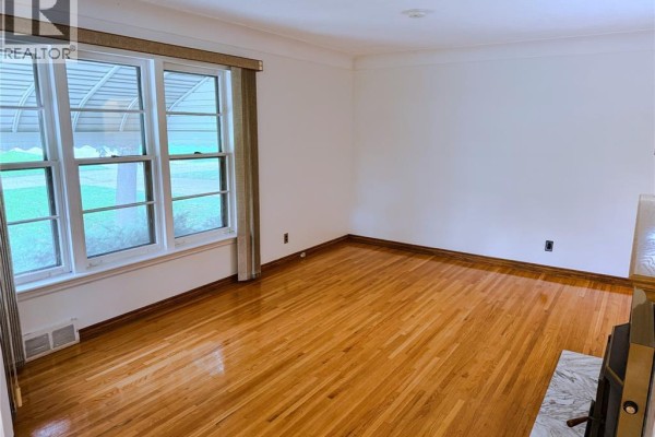 Empty living room with polished wood floors and a large bay window. - 3168 Church, Windsor