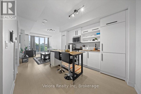 Open concept living area and kitchen with white cabinetry, stainless steel appliances, and island. - 317 - 560 Rideau Street, Ottawa