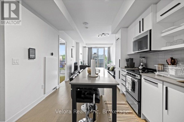 View down the open concept kitchen and living area toward the balcony and city view. - 317 - 560 Rideau Street, Ottawa