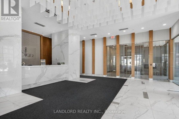 Modern apartment building lobby with a white marble reception desk and patterned accent walls. - 317 - 9506 Markham Road, Markham