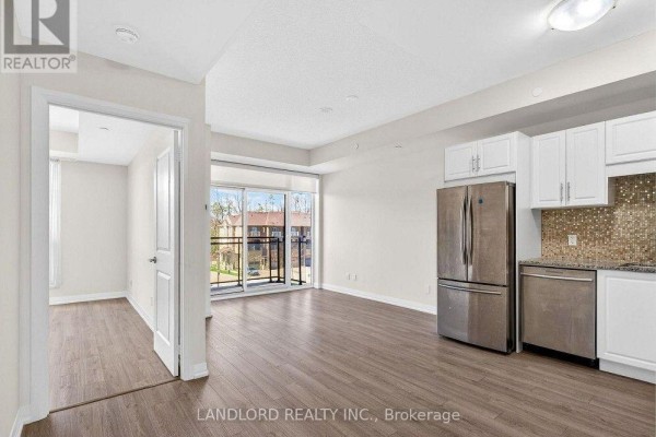 Living room and kitchen area with stainless steel appliances, white cabinets, and balcony access. - 317 - 9506 Markham Road, Markham