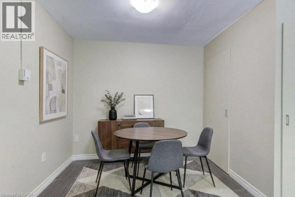 Dining area with a round table, four chairs, a wooden buffet, and artwork. - 317 Erb Street W Unit# 3, Waterloo