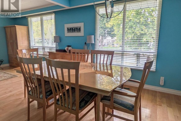 Dining room with a light wood table, six chairs, and blue walls overlooking a tree-lined yard. - 3170 Corry Crescent, Niagara Falls