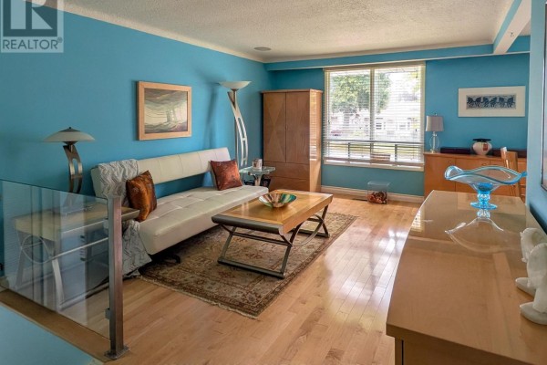 Living room with a white sofa, wooden coffee table, and blue walls with large windows. - 3170 Corry Crescent, Niagara Falls