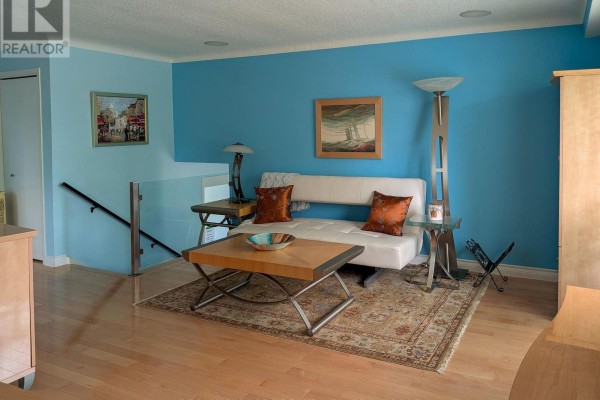 Living room with a white sofa, coffee table, glass railing, and bright blue accent walls. - 3170 Corry Crescent, Niagara Falls
