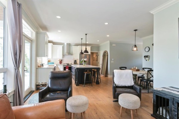 Living room with a stone fireplace, built-in shelving, hardwood floors, and large windows. - 3173 216 Street, Langley