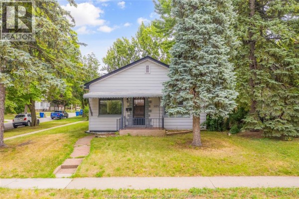 Aerial view of a white single-story house with a covered porch and mature trees in the yard. - 3173 Wyandotte St West, Windsor