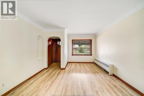 Interior living room with light beige walls, light wood laminate flooring, and a view through the window. - 3173 Wyandotte St West, Windsor