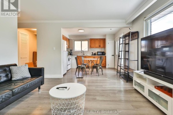 Living room with black leather sectional, white coffee table, and open kitchen. - 3174 Weston Road, Toronto