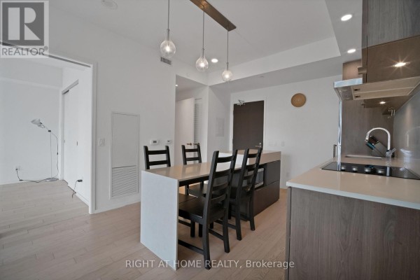 Kitchen island with chairs, looking towards the living area and balcony doors. - 318 - 12 Bonnycastle Street, Toronto