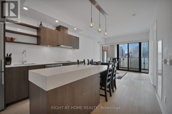 Kitchen and living area with balcony access and city view from large windows. - 318 - 12 Bonnycastle Street, Toronto