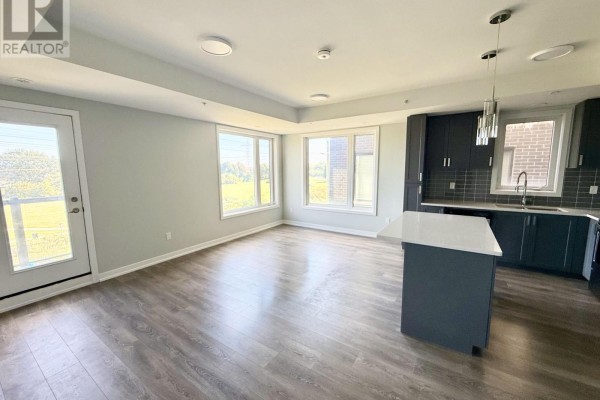 View of green fields from living room and kitchen with white island. - 318 - 1555 Kingston Road, Pickering