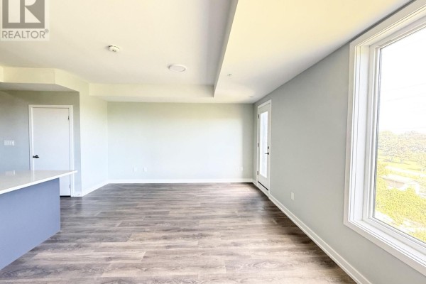 Empty living space with large windows and a door to a balcony. - 318 - 1555 Kingston Road, Pickering